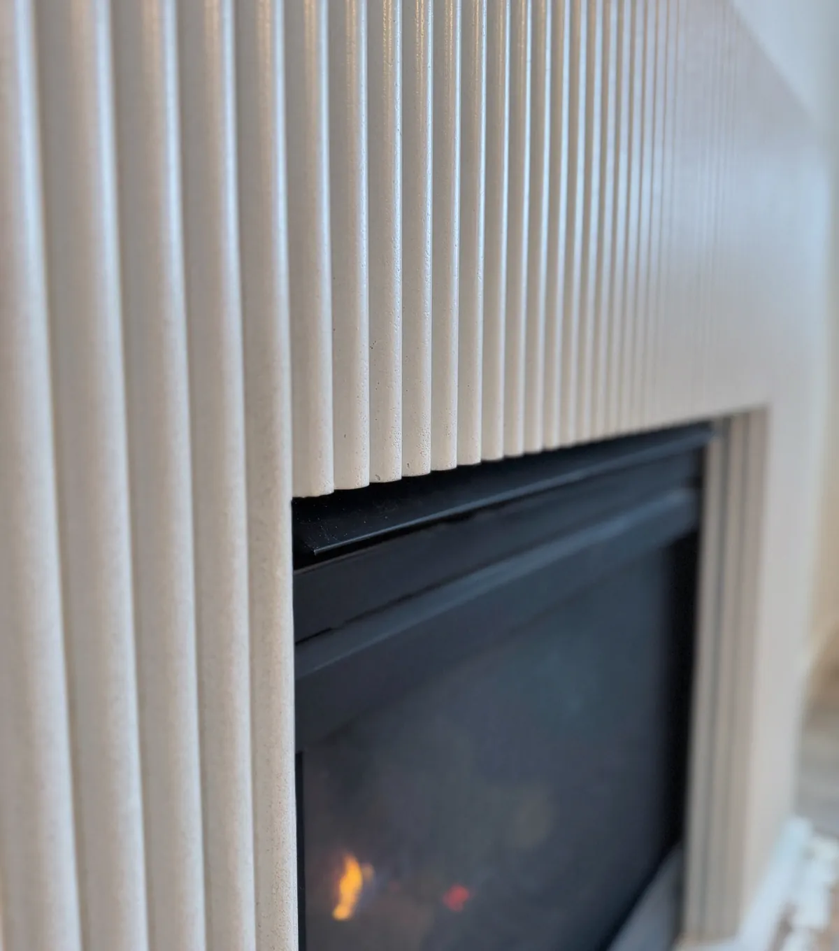 Fluted concrete fireplace surround with vertical reeding around the firebox